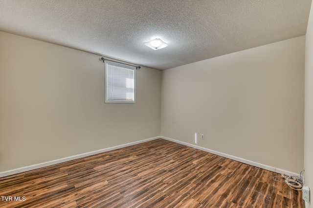 spare room featuring a textured ceiling, baseboards, and dark wood-type flooring