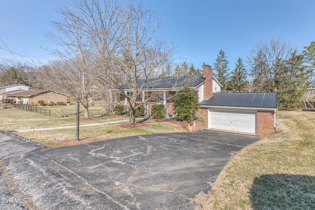 view of front of property featuring metal roof, solar panels, brick siding, a front lawn, and a chimney