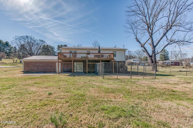 rear view of house with brick siding, fence, a lawn, and a wooden deck