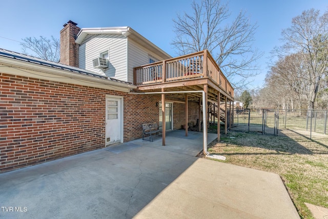 rear view of house with a deck, brick siding, fence, a gate, and a chimney