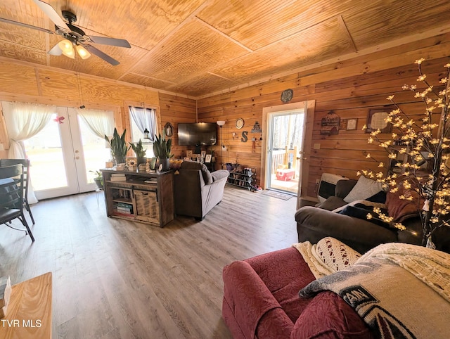 living area featuring wooden ceiling, wooden walls, a ceiling fan, and wood finished floors