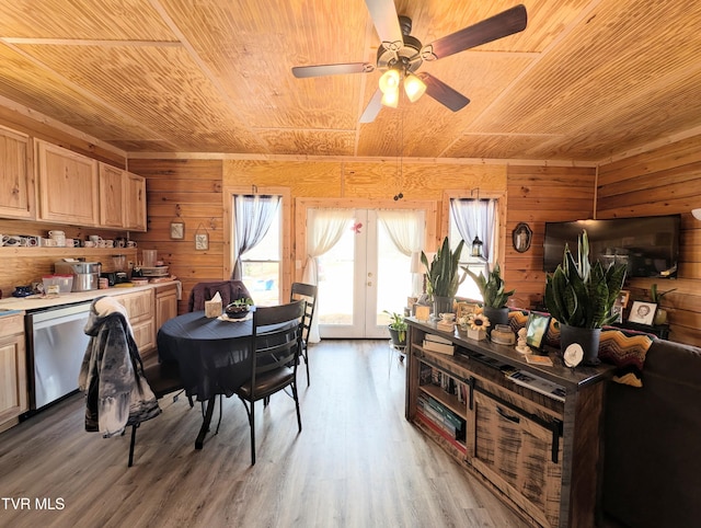 dining room featuring light wood finished floors, wood ceiling, wooden walls, and french doors