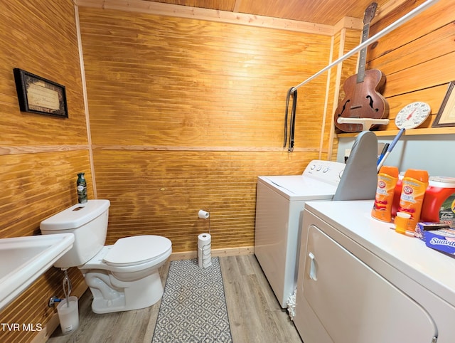 clothes washing area featuring washer and dryer, wood ceiling, wooden walls, light wood-type flooring, and laundry area