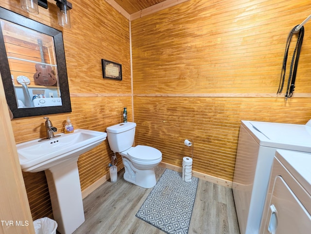 bathroom with toilet, separate washer and dryer, and wood finished floors