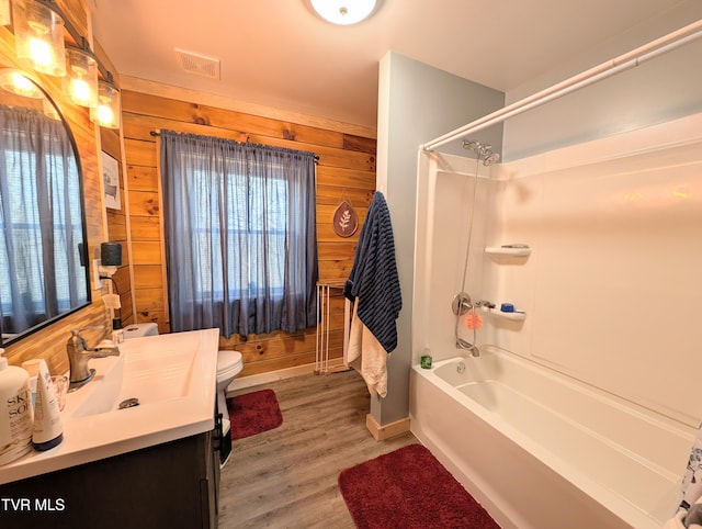 full bath with visible vents, wood walls, toilet, and wood finished floors