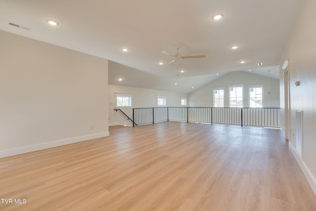 unfurnished room featuring a wealth of natural light, visible vents, vaulted ceiling, and light wood-style flooring