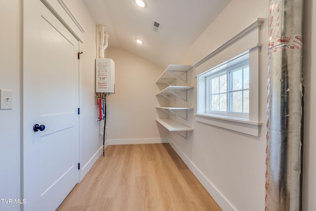 spacious closet with visible vents, vaulted ceiling, and light wood finished floors