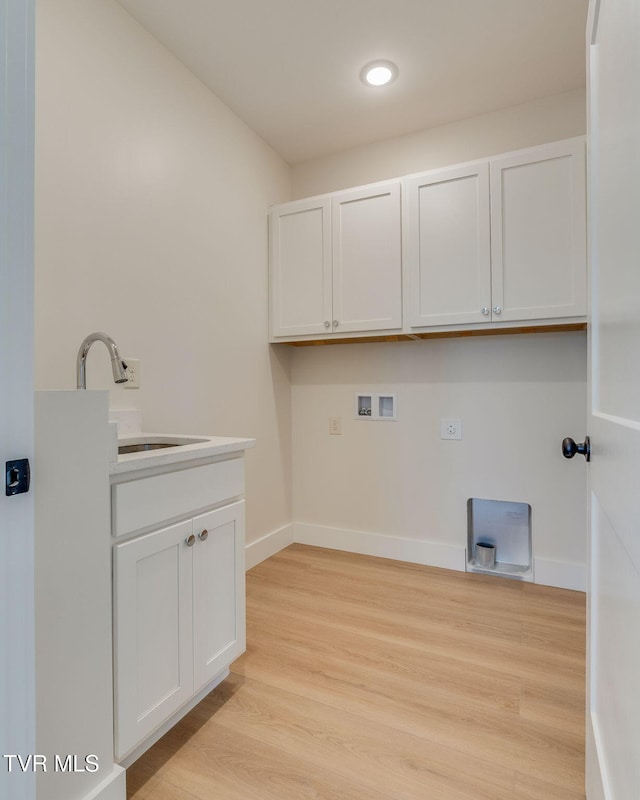 washroom with hookup for a washing machine, light wood-style flooring, baseboards, and a sink