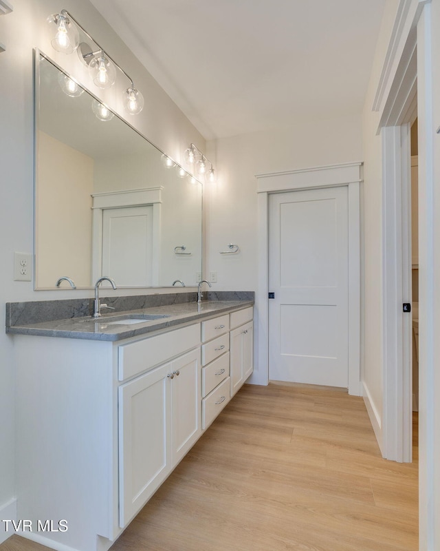 bathroom featuring double vanity, wood finished floors, and a sink