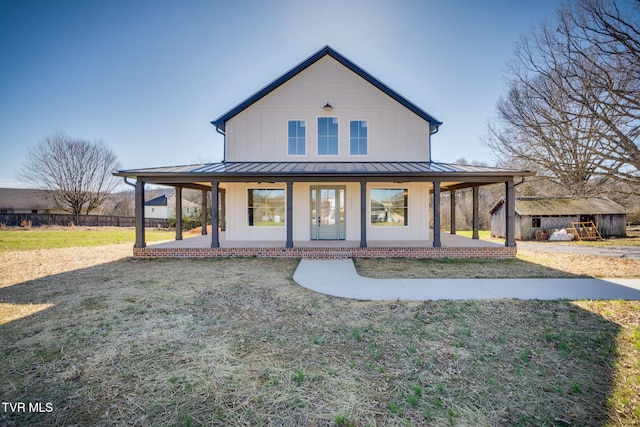 view of front facade with a standing seam roof, metal roof, a front lawn, and board and batten siding