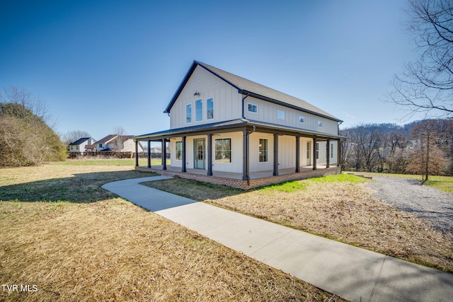 view of front of house with board and batten siding, covered porch, and a front lawn