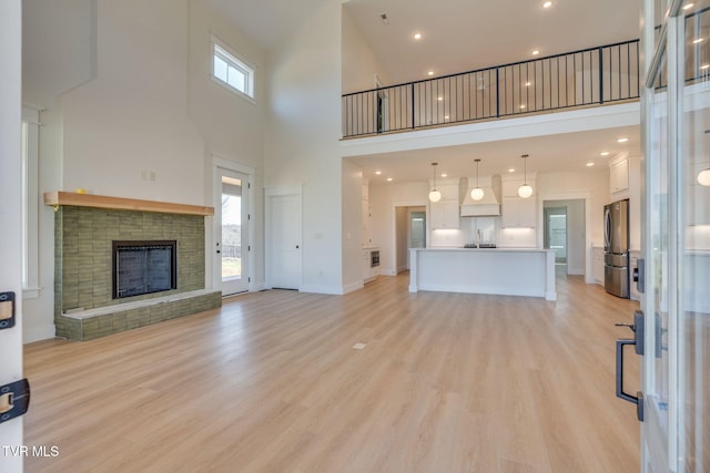 unfurnished living room with light wood-type flooring, a fireplace, and a wealth of natural light