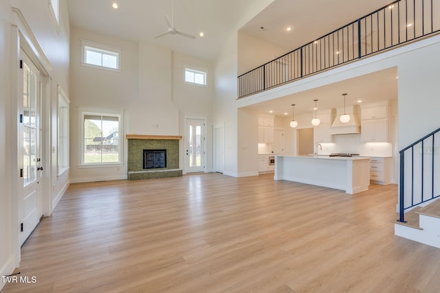 unfurnished living room with light wood-type flooring, a wealth of natural light, stairway, and a sink