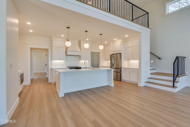 kitchen featuring light countertops, stainless steel fridge, light wood-style flooring, and white cabinetry