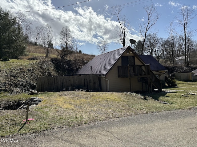 view of side of property with stairway, metal roof, and fence