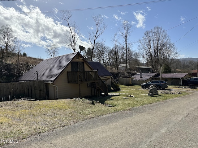 view of side of home with stairway, metal roof, and fence