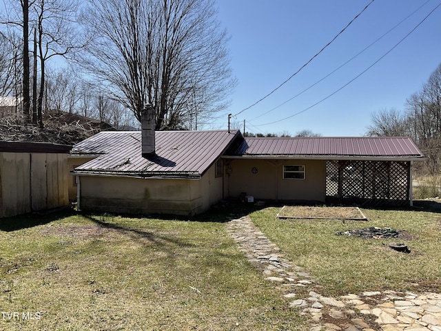 view of side of property featuring metal roof and a yard