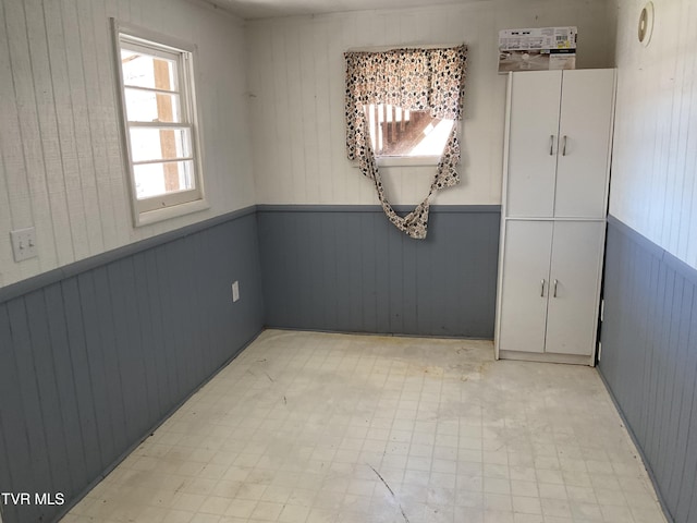 unfurnished dining area with light floors and a wainscoted wall