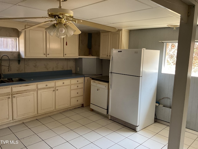 kitchen with white appliances, ceiling fan, a sink, dark countertops, and cream cabinets