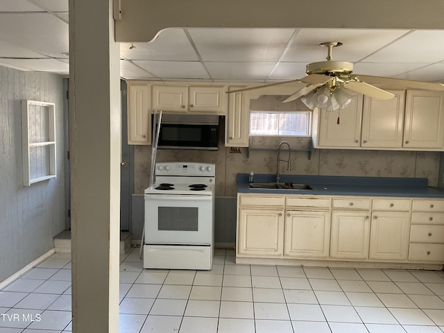 kitchen with a sink, stainless steel microwave, cream cabinets, and white electric range oven