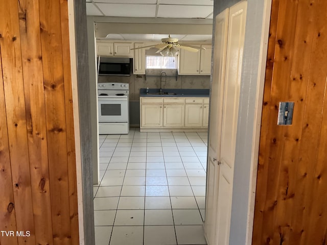 kitchen with stainless steel microwave, ceiling fan, light tile patterned floors, electric range, and a sink