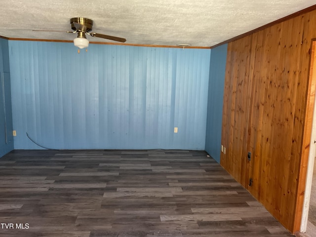 unfurnished room with ornamental molding, a textured ceiling, wood finished floors, wooden walls, and ceiling fan