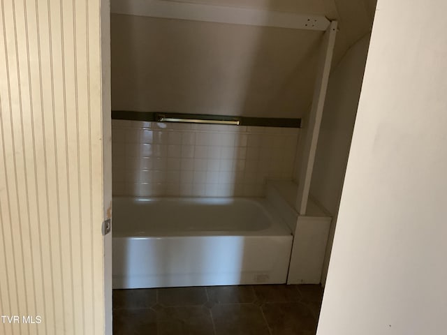 bathroom with tile patterned floors and a bath