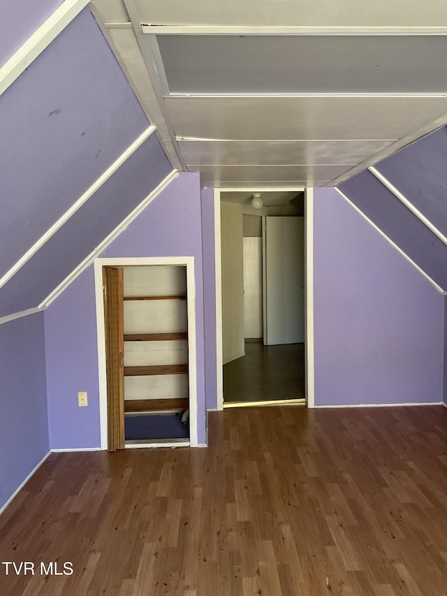 additional living space with wood finished floors and vaulted ceiling