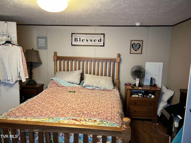 bedroom with crown molding, a textured ceiling, and wood finished floors