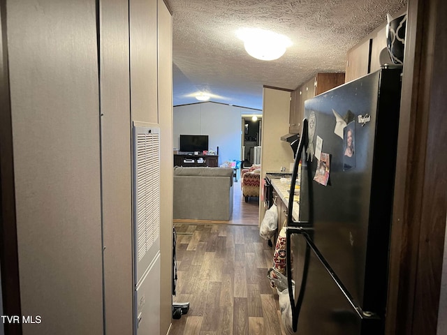 kitchen with freestanding refrigerator, open floor plan, vaulted ceiling, a textured ceiling, and wood finished floors