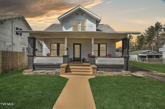 bungalow with a porch, a yard, and fence