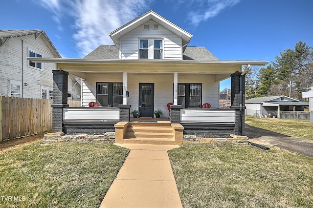 bungalow-style home featuring a porch, fence, a shingled roof, and a front lawn