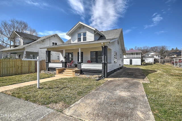 bungalow-style house featuring a porch, a front yard, fence, and an outdoor structure