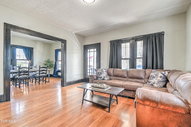 living room featuring a textured wall, a textured ceiling, and light wood finished floors