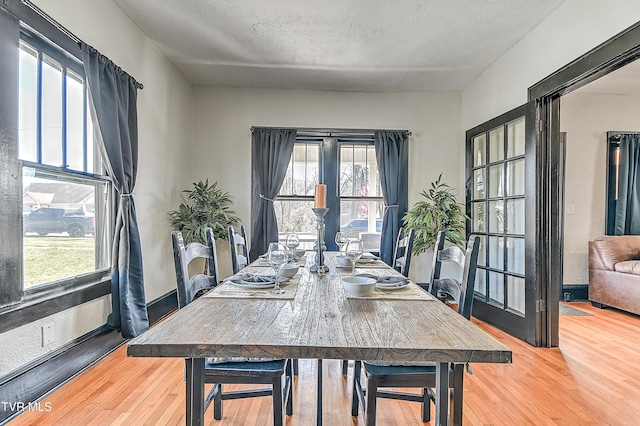 dining area featuring a textured ceiling, baseboards, and wood finished floors