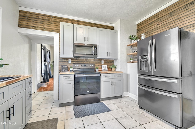 kitchen featuring a sink, appliances with stainless steel finishes, a textured ceiling, and light tile patterned flooring