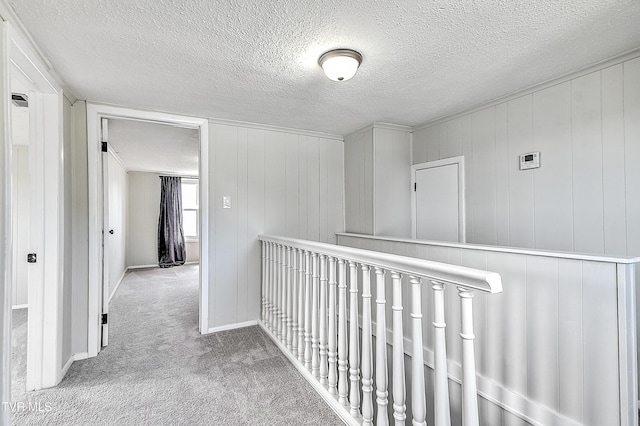 hall with carpet flooring, a textured ceiling, and baseboards