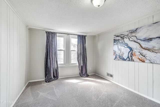 carpeted empty room featuring visible vents and a textured ceiling