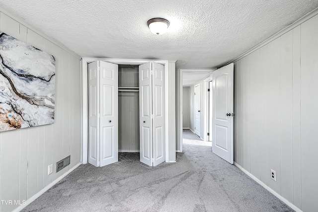 unfurnished bedroom featuring a textured ceiling, a closet, and carpet