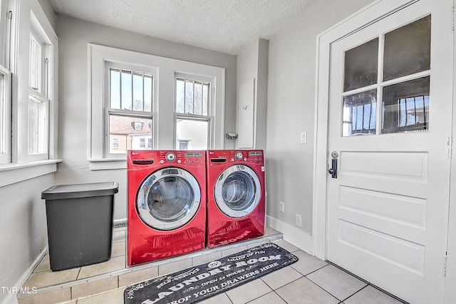 laundry room featuring washing machine and dryer, a textured ceiling, tile patterned flooring, laundry area, and baseboards