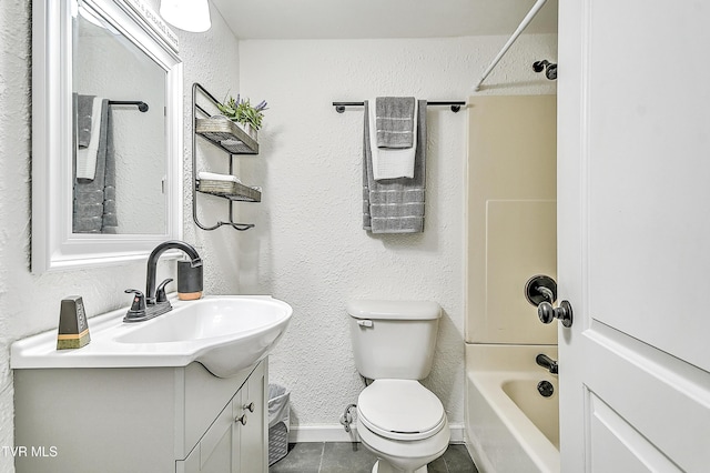 bathroom with baseboards, bathing tub / shower combination, toilet, a textured wall, and vanity