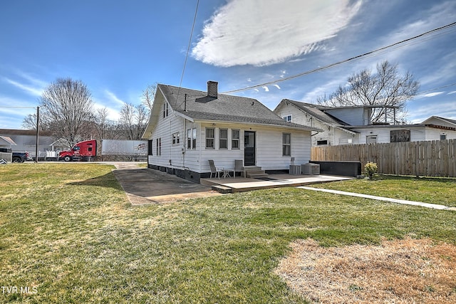 back of property with entry steps, a patio, fence, a yard, and a chimney