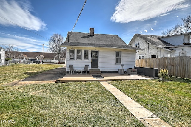 rear view of property with a yard, entry steps, fence, and a chimney