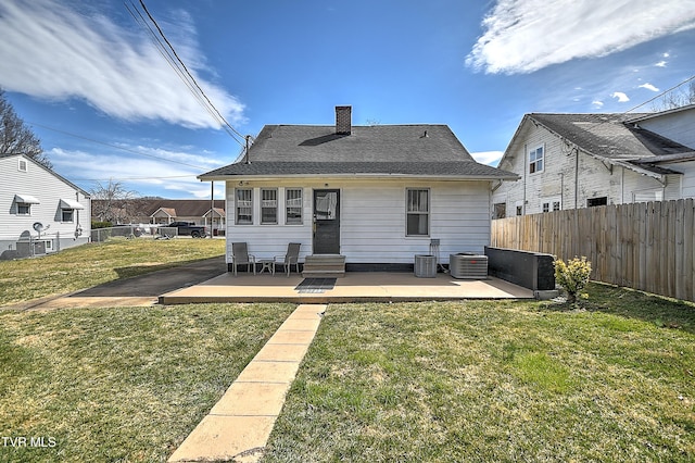 rear view of property featuring entry steps, a yard, central AC unit, and fence