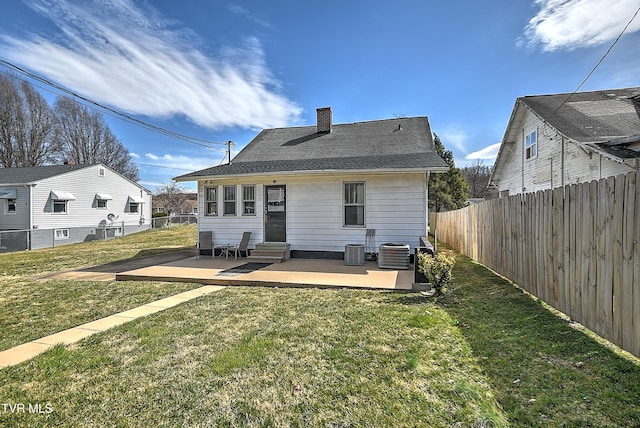 back of property with entry steps, a yard, a fenced backyard, and central air condition unit