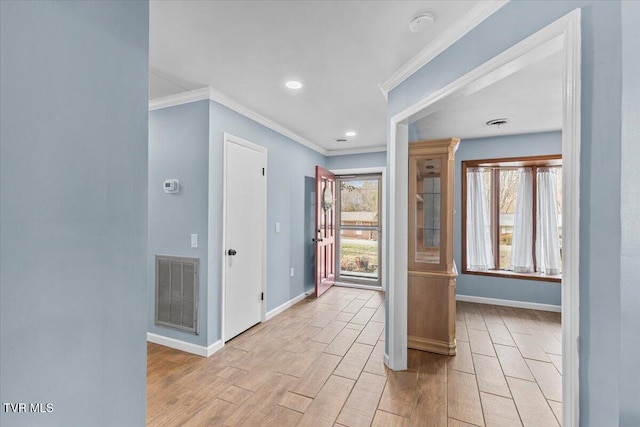 interior space with baseboards, visible vents, light wood-style flooring, and ornamental molding