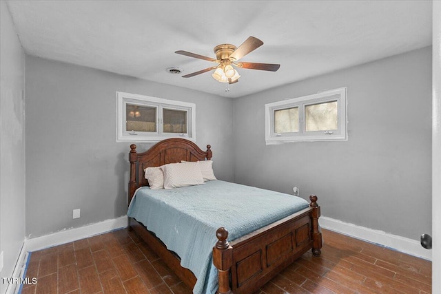 bedroom with ceiling fan, visible vents, baseboards, and wood finished floors