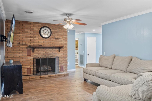 living room featuring crown molding, visible vents, a brick fireplace, wood finished floors, and baseboards