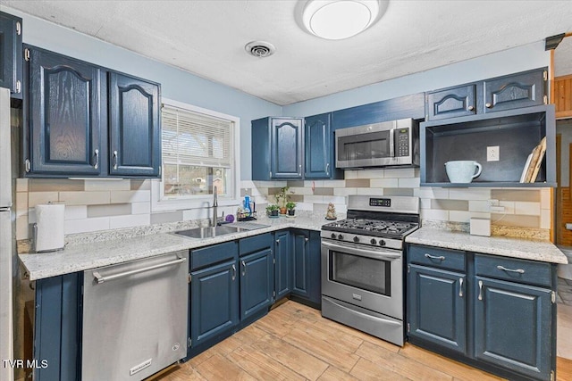 kitchen featuring blue cabinets, visible vents, appliances with stainless steel finishes, and a sink