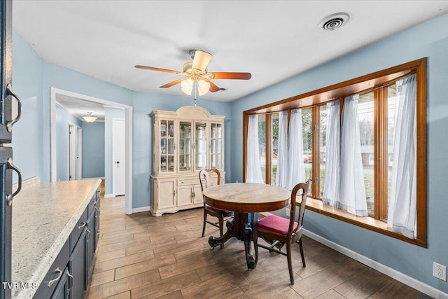 dining space with ceiling fan, dark wood-style flooring, visible vents, and baseboards